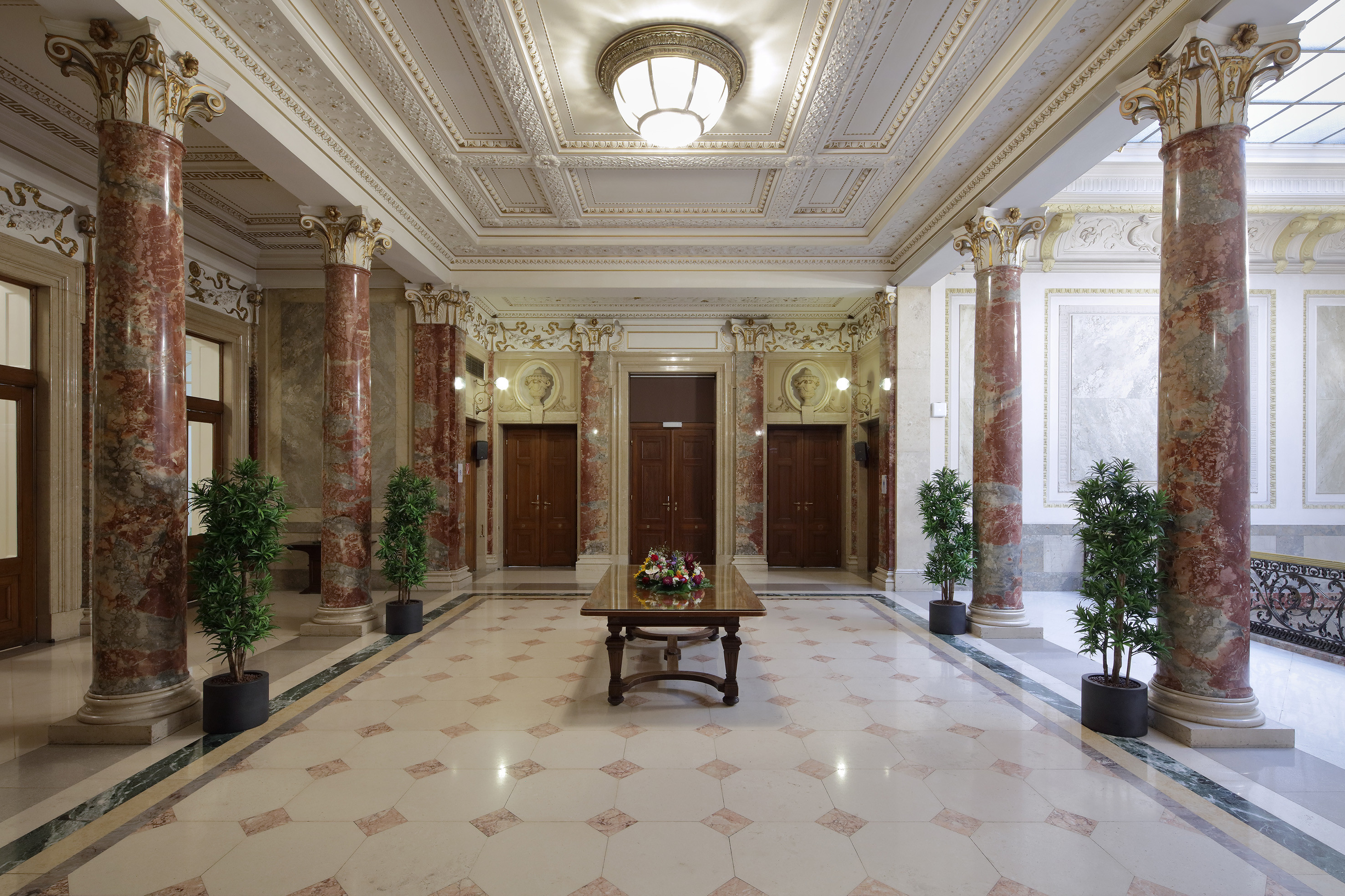 Sicht ins Foyer zum kleinen Festsaal mit vier Marmorsäulen, großem braunen Holztisch mit Blumendekoration