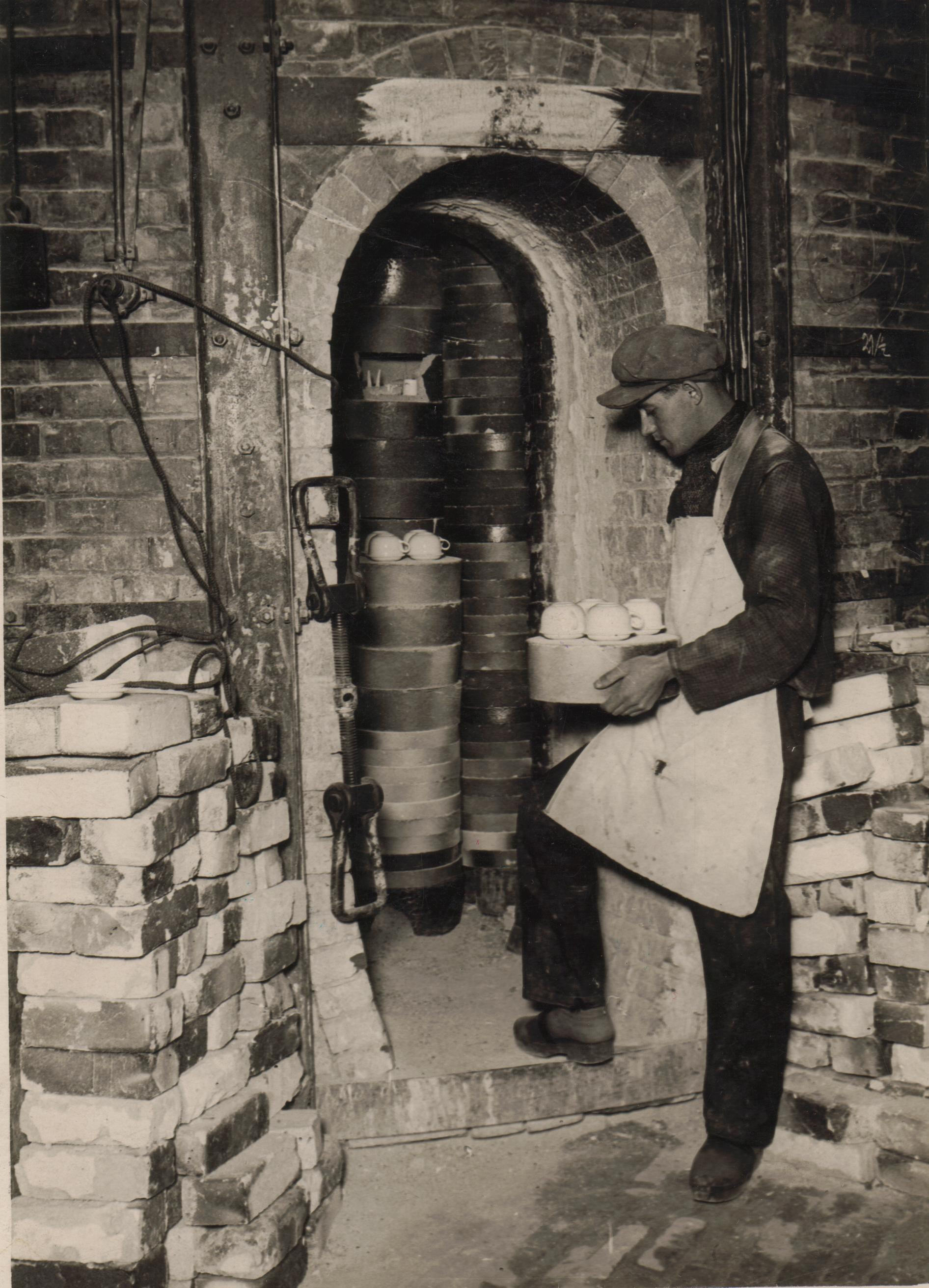 Blick in den Brennofen mit einem Mitarbeiter, der Porzellan einsetzt, um 1925